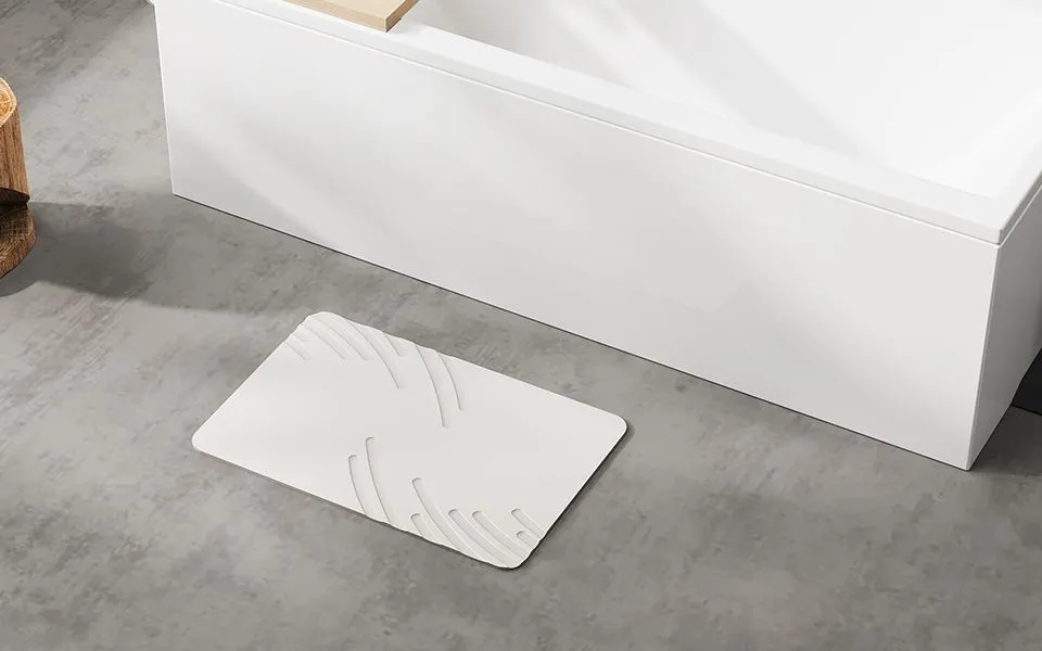 ZIKIBL stone bath mat in White Feather, feather pattern, beside a bathtub