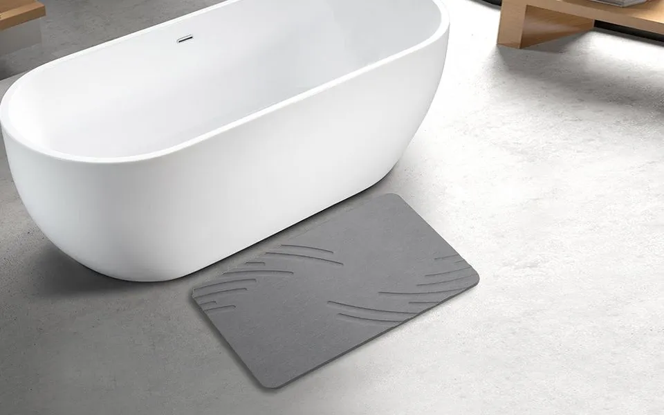 ZIKIBL stone bath mat in Grey Feather, feather pattern, beside a bathtub